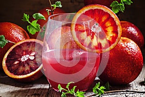 Red orange juice in a large glass, vintage wooden background, se