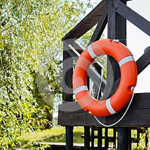 A red and orange lifebuoy hangs on the terrace near the fishing pier