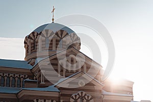 A red-orange orthodox chirch with a sun comming from it\'s side