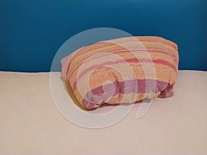 Red and orange pillow on the bed sheets on the blue background