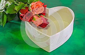 Red and orange roses flowers with heart shape box, Valentines Day, green light bokeh background, close up