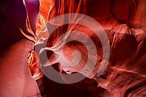 Red-orange sandstones stacked in layered fire waves in a narrow sandy labyrinth in Lower Antelope Canyon in Page Arizona