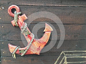 Red and orange wooden anchor sculpture sign mounted onto wooden