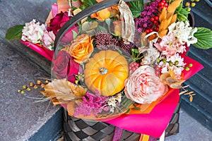 Red orange yellow autumn bouquet with rose flowers, fall leaves and pumpkin