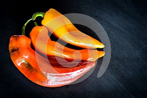 Red, Orange and yellow organic sweet pointed peppers on a blackboard, natural light