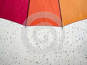 Red orange yellow umbrella with rain water drop in background