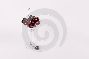 Red organic sweet cherries in martini glass on white background