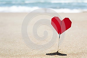 Red origami heart on the beach with blank space