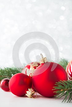 Red ornaments and xmas tree on glitter holiday background. Merry christmas card.