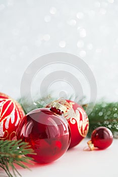 Red ornaments and xmas tree on glitter holiday background. Merry christmas card.