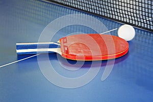 Red paddle, tennis ball on blue ping pong table