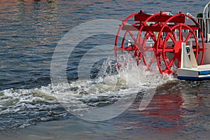 Red paddle wheel on a boat churning the water photo