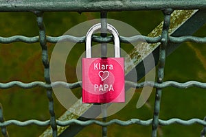 Red padlock with names on fence