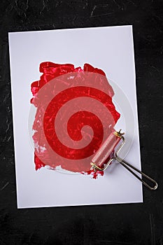 Red paint background with a roller, an abstract texture