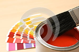 Red paint can, brush and color palette on table, closeup. Space for text