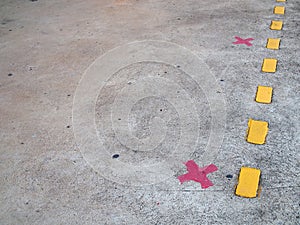 red paint cross marks on cement floor of train station platform with yellow dividing line