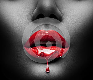 Red Paint drips from the lips, lipgloss dripping from sexy lips, bright liquid drops on beautiful model girl`s mouth, black skin