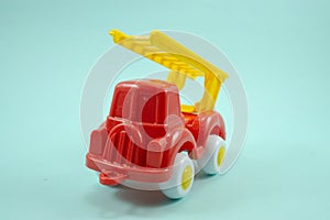 Red paint plastic toy fire truck with yellow ladder isolated on turquoise