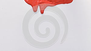 Red paint spreads on a white background. Copy space.