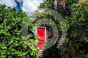 Red painted door in a green garden of an old Dutch town with traditional wooden vintage wooden houses