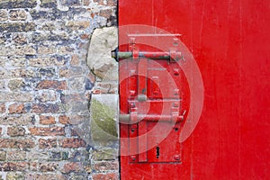 Red painted door with locks and brickwork