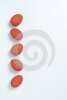Red painted easter eggs aligned in a row on white background