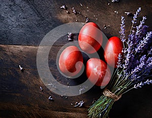 Red painted Easter eggs with lavender on dark rustic background