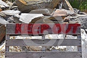 Red painted pallet sign stating `KEEP OUT`
