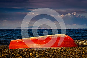 Red Painted Reverse Rowboat On Shoreline