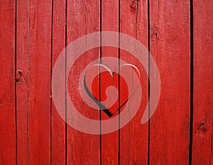 Red painted wooden wall with heart as a symbol of love and friendship