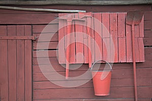 Red-painted wooden wall of a shed with garden tools