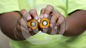 Red palm oil seeds on Child`s hands