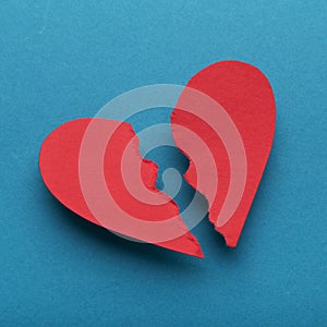 Red paper broken heart on bright blue background
