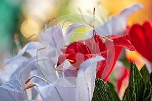 Red paper flower among white flowers blurred, origami