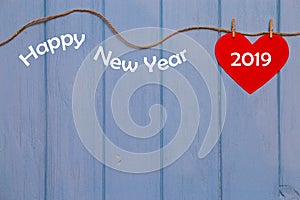 Red paper heart with 2019 happy new year text on blue wooden background, banner with copy space for text