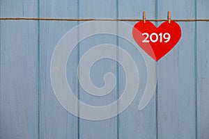 Red paper heart with 2019 happy new year text on blue wooden background, banner with copy space for text