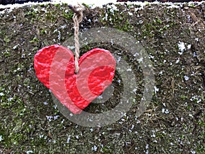 Red paper heart hangs on the pin on a rustic background