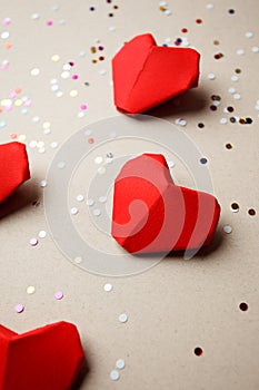 Red paper hearts and party confetti on gray background. Top view. Valentine`s Day pattern. Symbol of love. Copy space