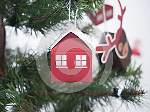 Red paper house with Windows hanging on Christmas tree.