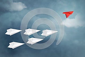 Red paper plane flying in a different direction than the white ones. Cloudy sky. Copy space. The concept of innovative solutions,