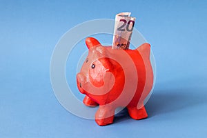 red papier mache piggy bank with 20 Euros