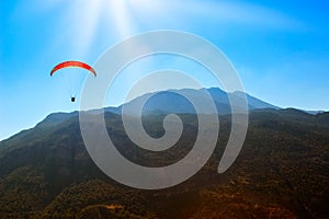 Red parachute in the sky above the mountains.