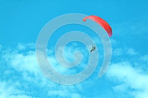 Red paraglider on the blue Sky