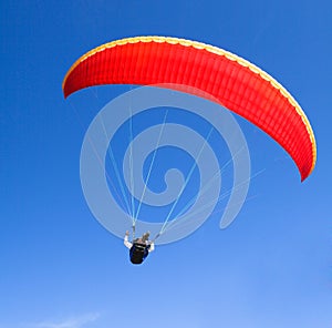 Red paraglider on the blue sky