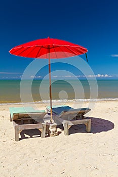 Red parasol with deckchair on tropical beach