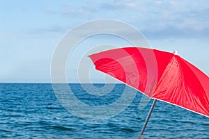 Red parasol umbrella on tropical island beach. Colourful sunshade in the beach on sunny summer day. Holiday relaxation
