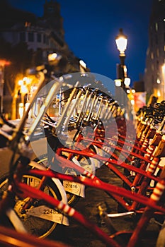 Red parked rental bikes at night perspective shot