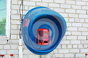 Red payphone in the blue booth.