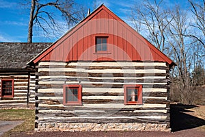 Red peaked roof and log construction of a colonial house