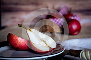 A red pear cut in half and other juicy red battler pears in a basket. Organic and natural products. Healthy food